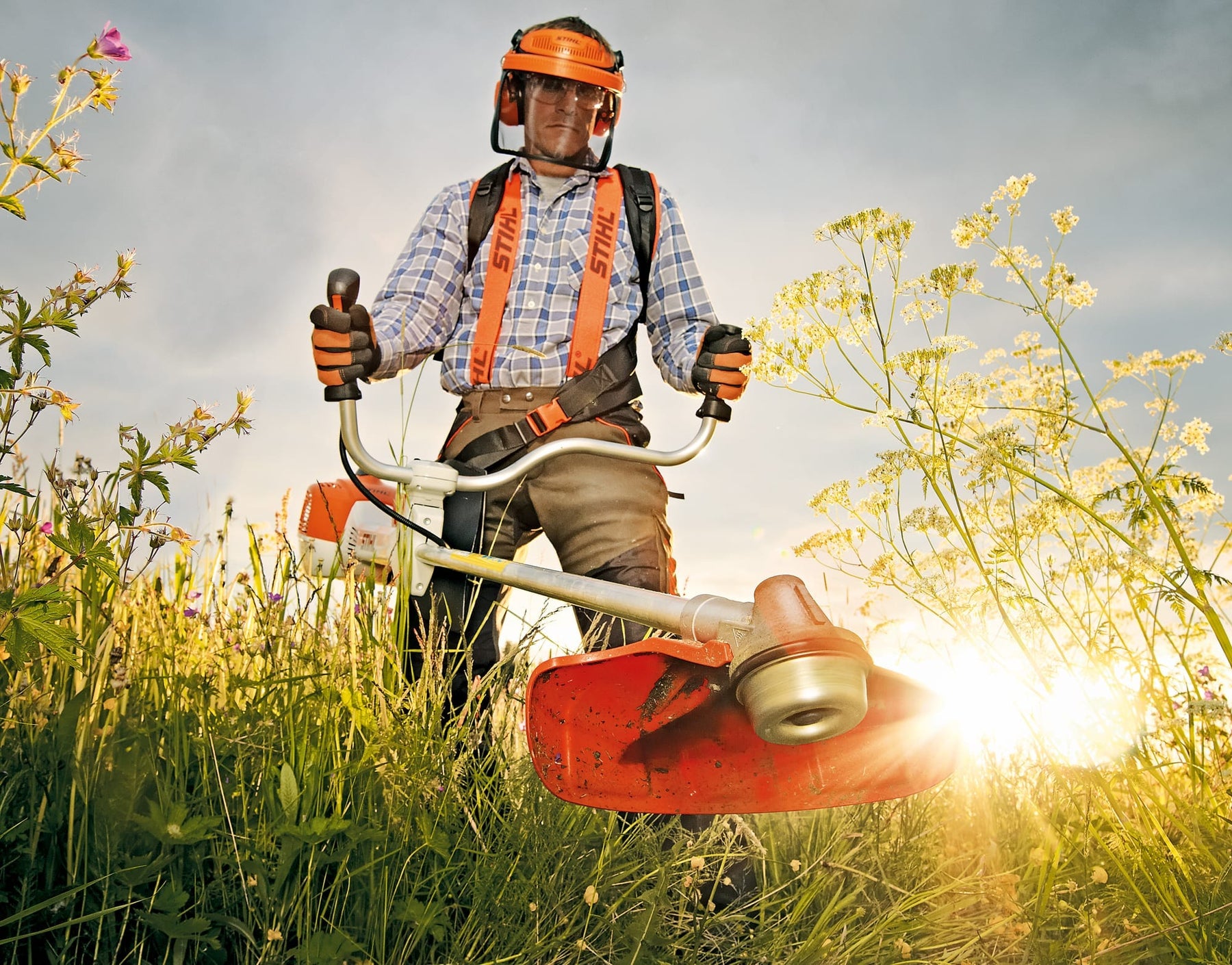 Man using Stihl heavy duty petrol brush cutter to cut weeds in the hot sun. High quality image looks very attractive